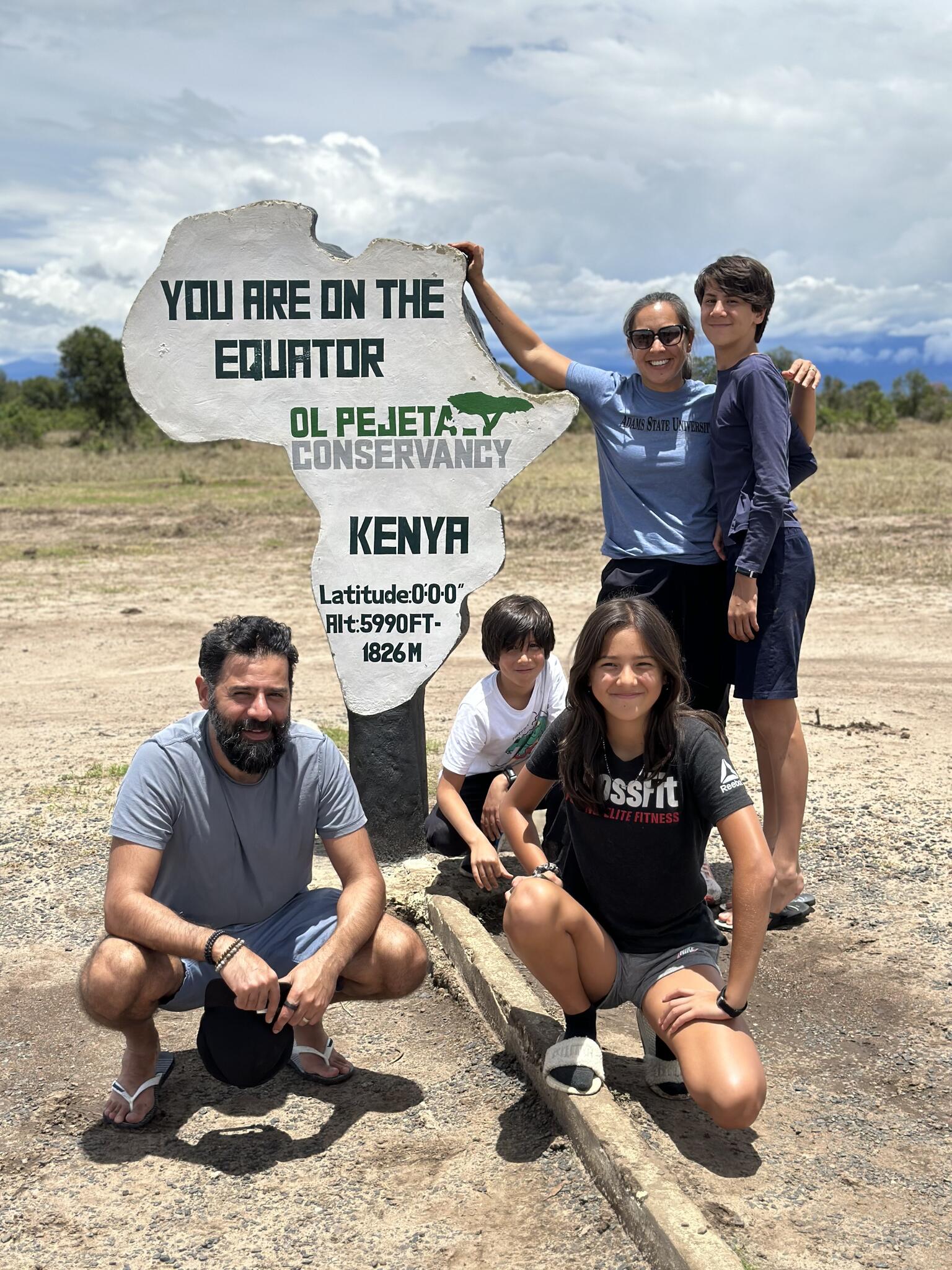 Jessica Hajee poses with her husband and children by an equator marker outside in Kenya