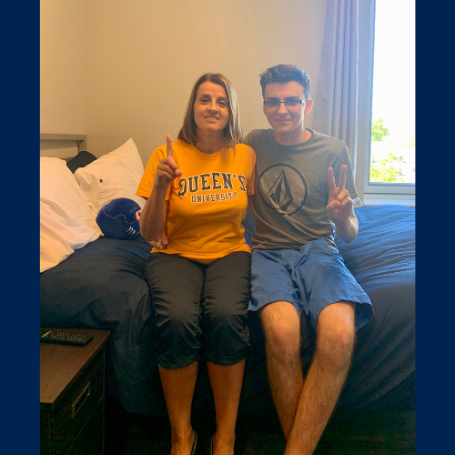 Rose Heron sits with her son on a bed in a residence. Rose holds up the number '1' with her fingers and her son holds up the number '2' with his fingers.