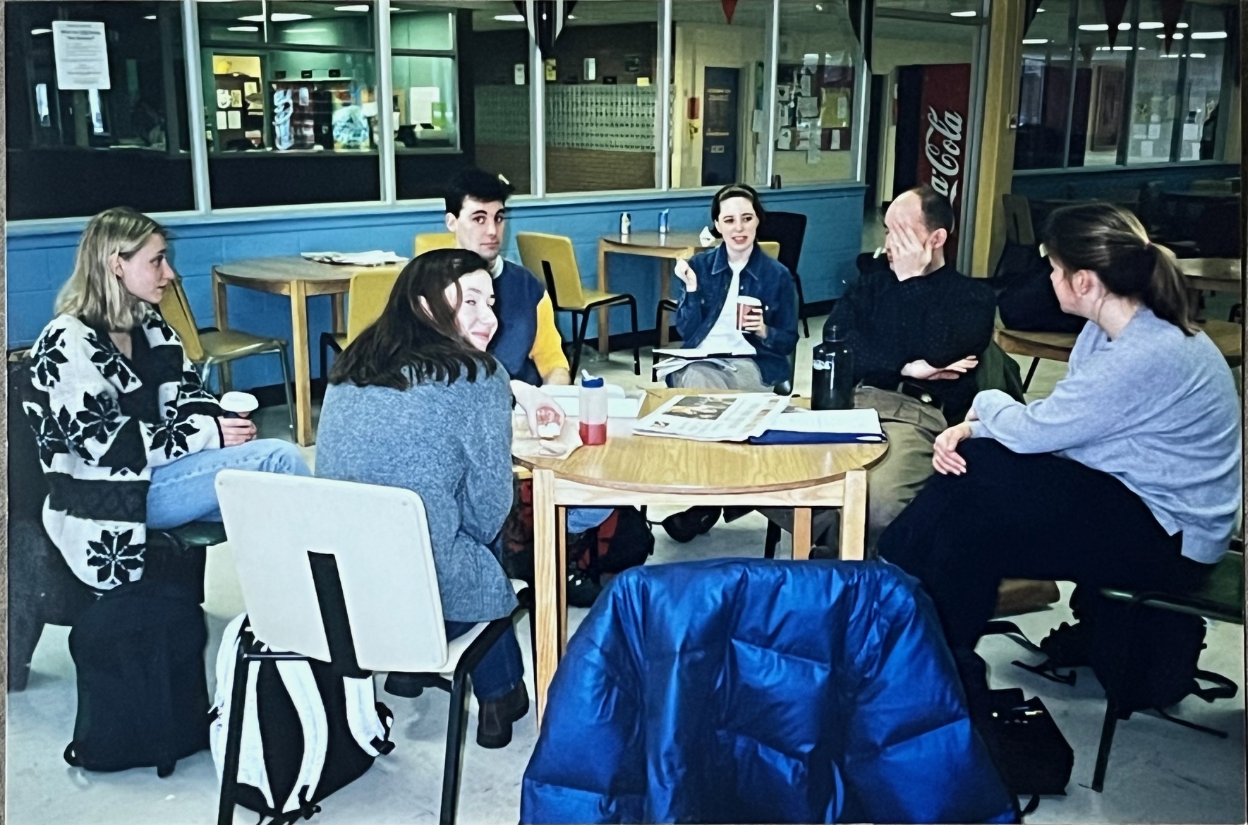 Students sit around a table with windows to their left.