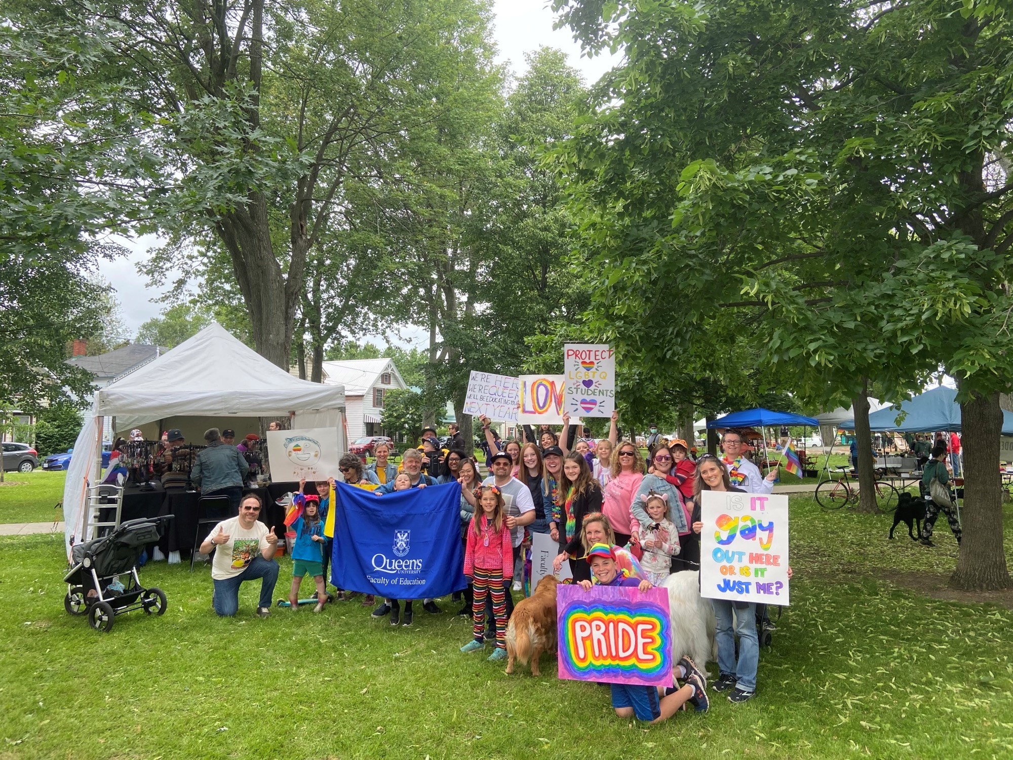 A group of people holding signs and banners poses for a photo in a park.