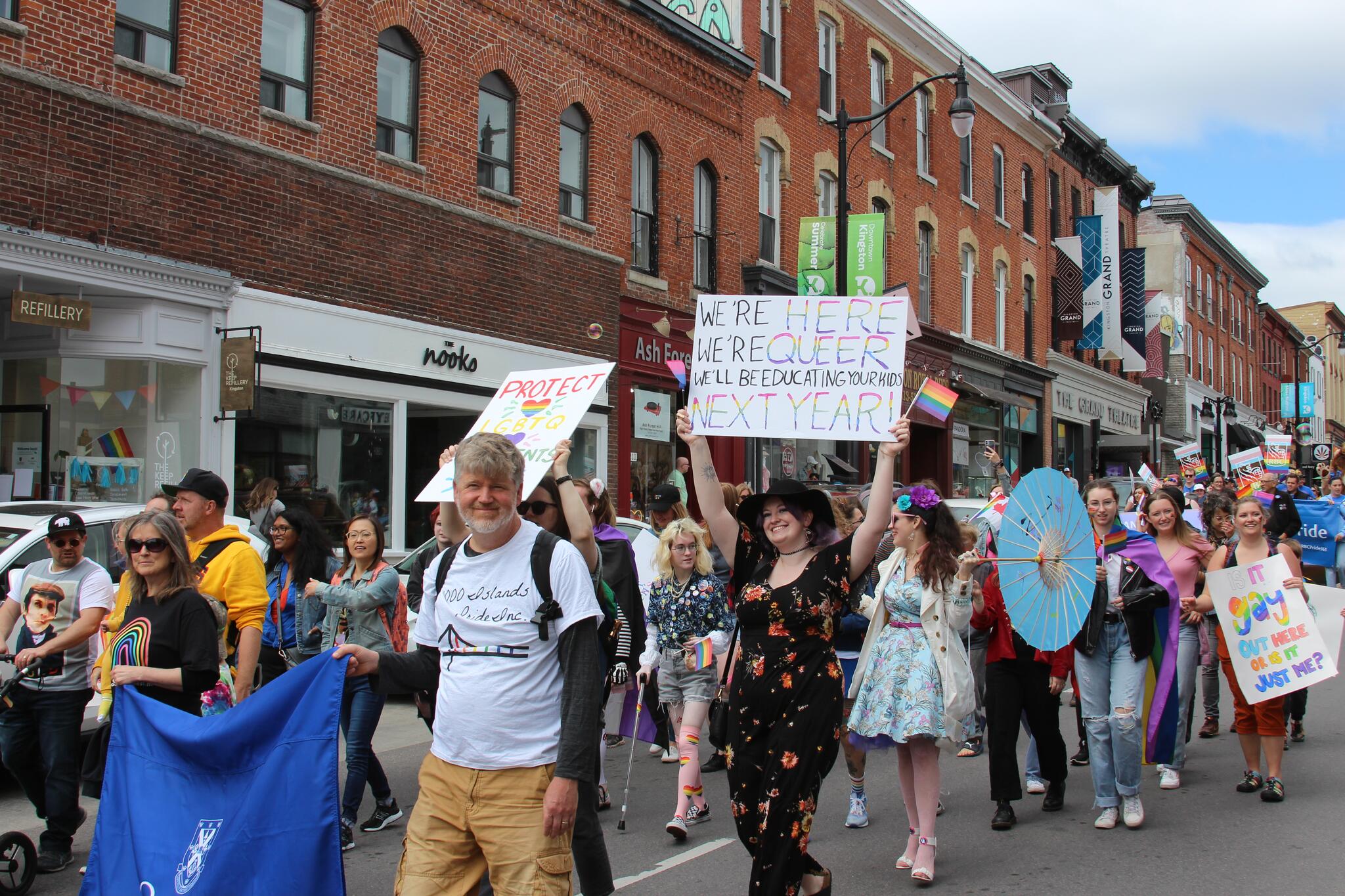 A group of people with signs, and a banner march down a street.