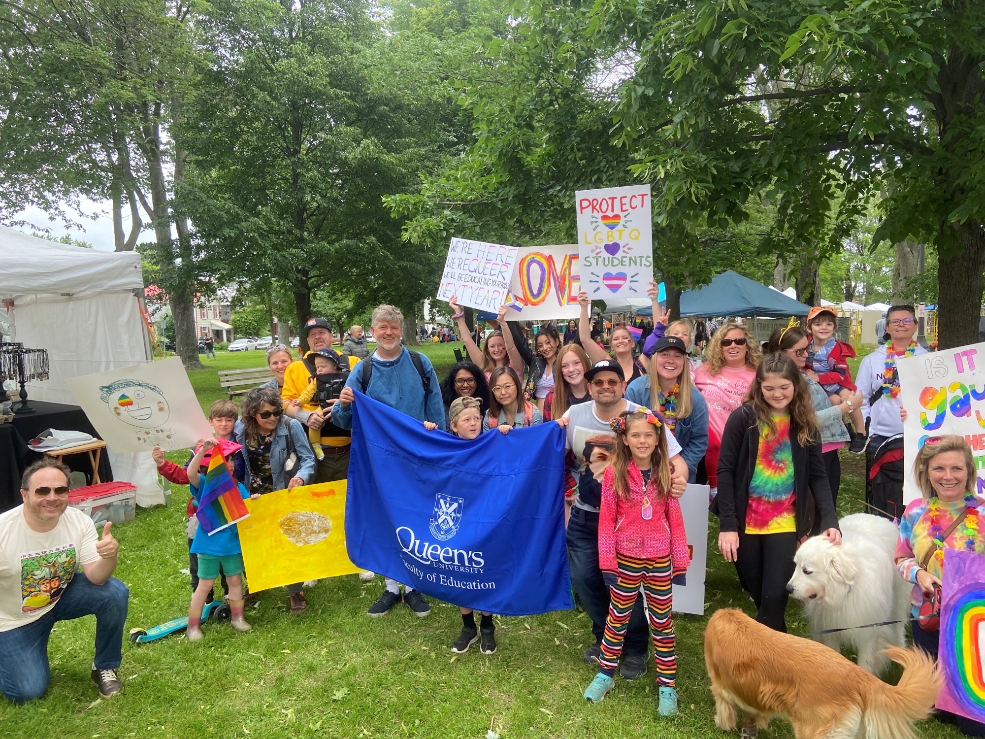 A group of people in rainbow clothing smiles for a photo in a park