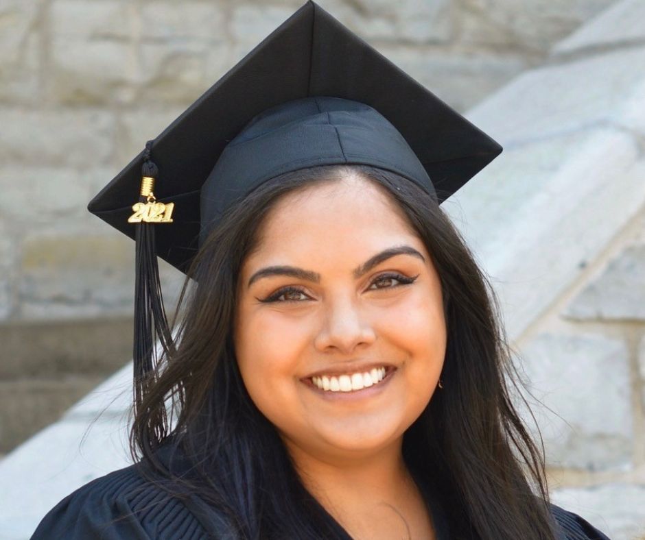 Jessica Dassanayake smiles wearing a graduation cap and gown.