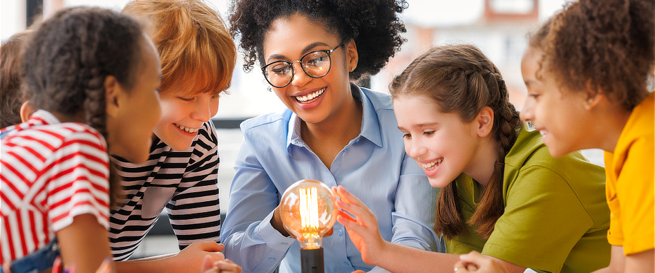 A teacher working with a lightbulb with four young students