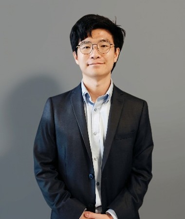 An Asian man wearing glasses with a suit on 