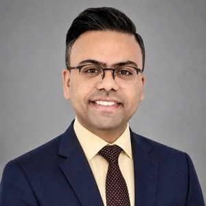 A headshot of Farid he is wearing a tie and suit