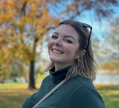 Kristen Fontaine a woman with blond hair smiles outside on a fall day with a tree in the background
