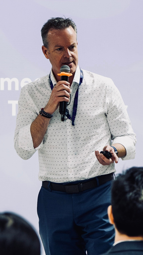 A white man in a button up shirt holding a microphone