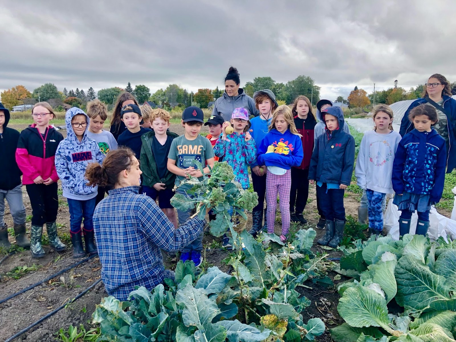 Emily Duncan displays a large harvested vegetable to a group of students.