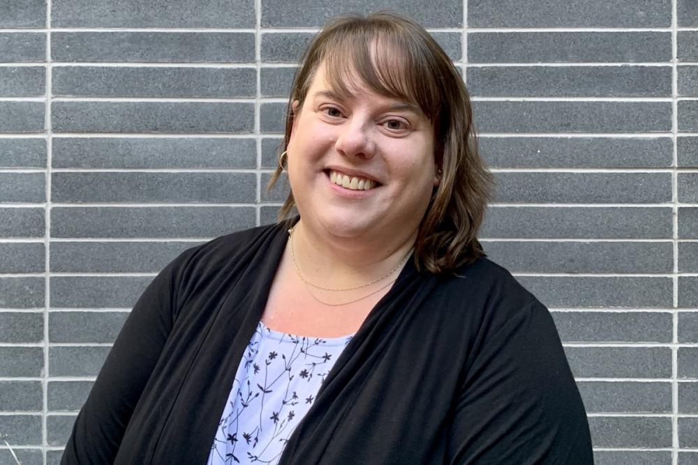 Melissa Balson smiles in front of a brick wall