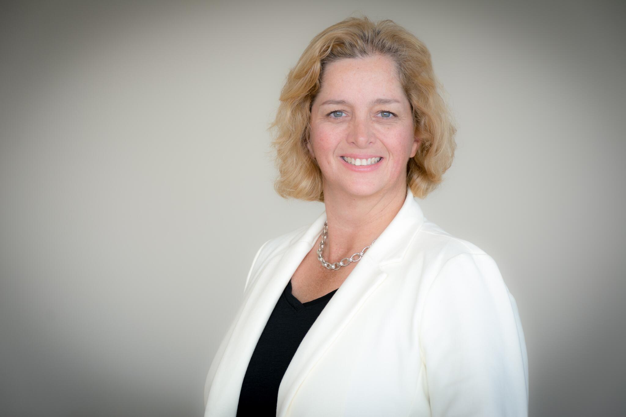 Heather Morrison smiles wearing a white jacket and black shirt.