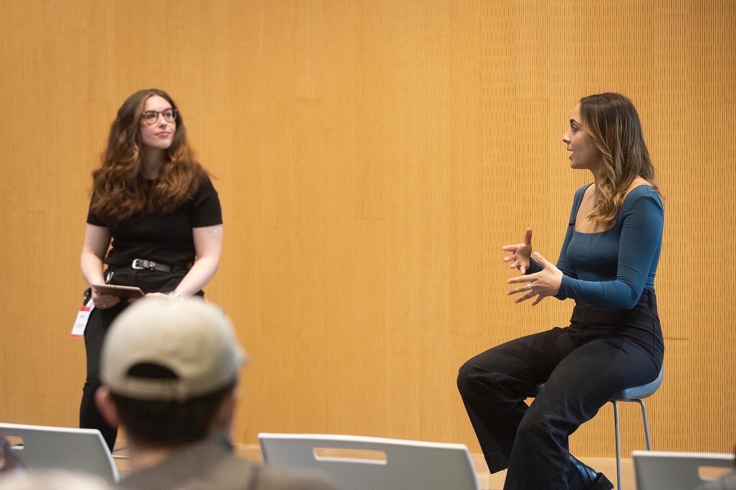 Two women sit across from each other speaking.