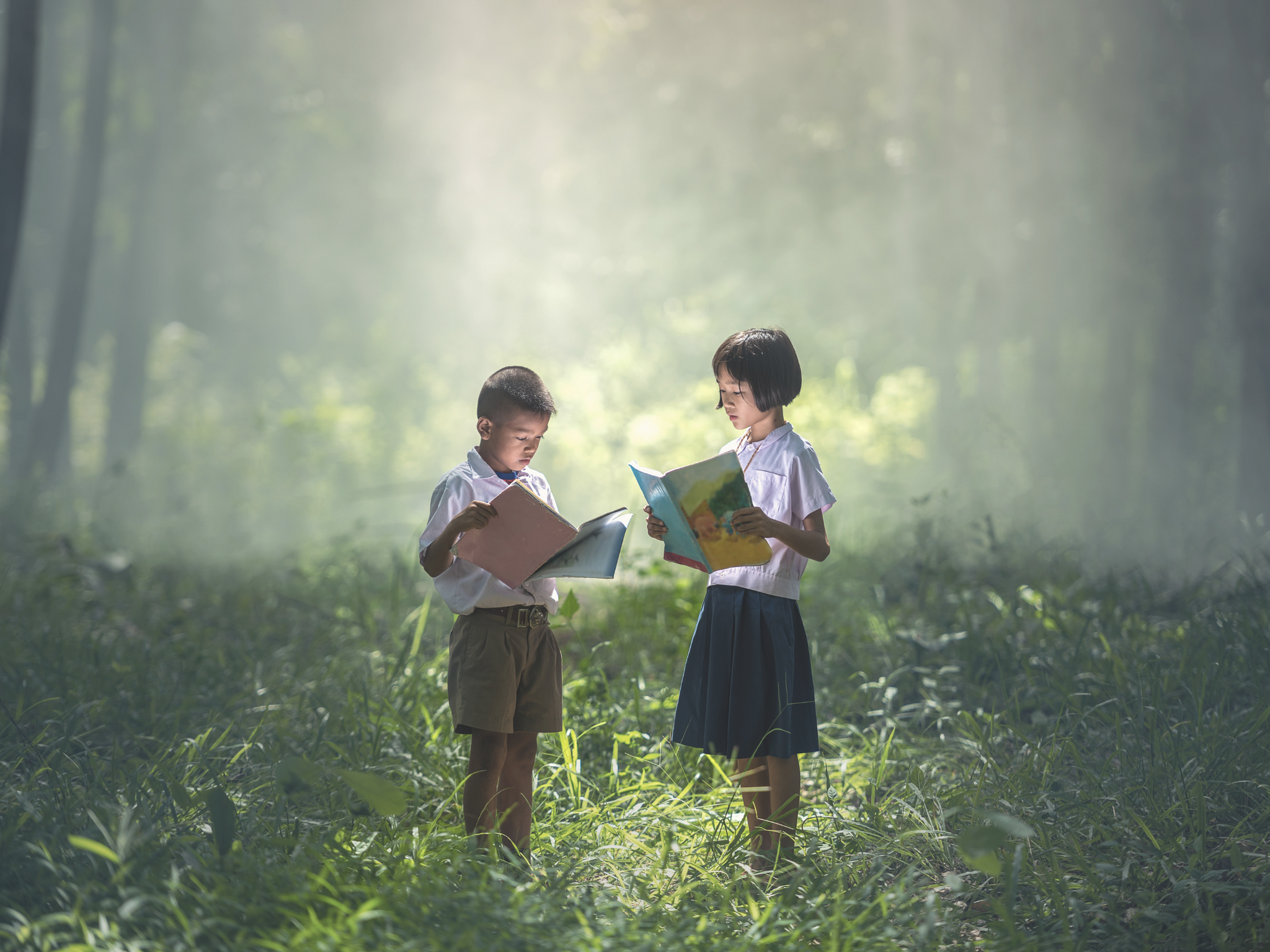 Two children reading books in nature 