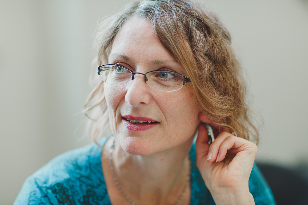 white woman looks to the side of the camera wearing a blue shirt 