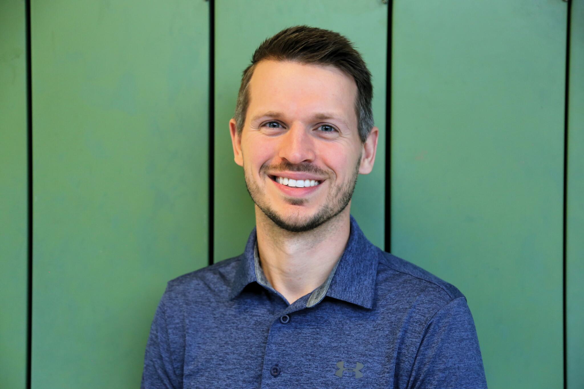 A man standing in front of a green background
