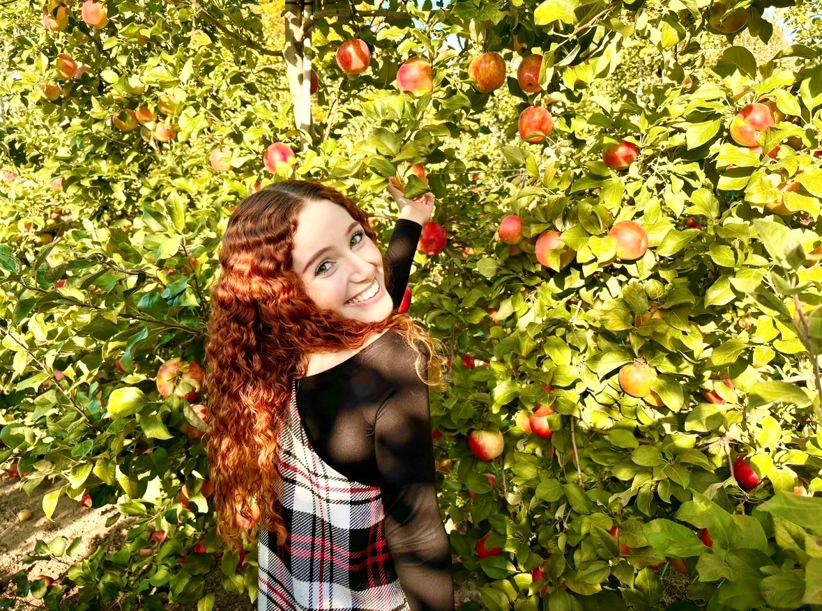 A woman with red hair picking apples