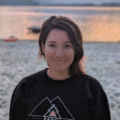 A woman smiling on a beach at sunset