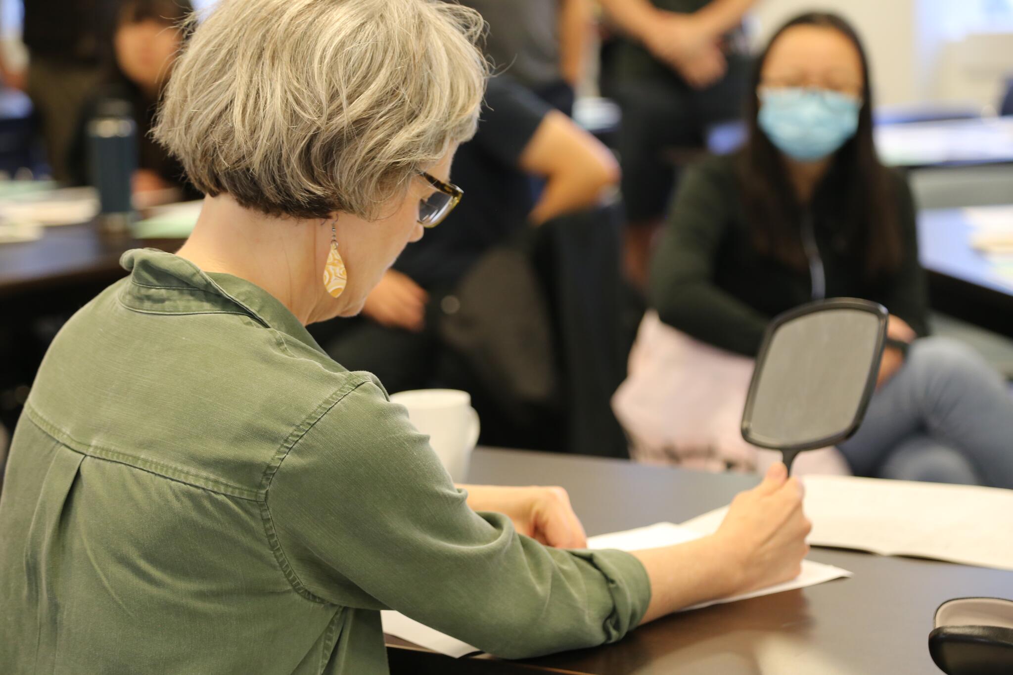 An artist looks in a mirror with one hand and draws with the other hand.