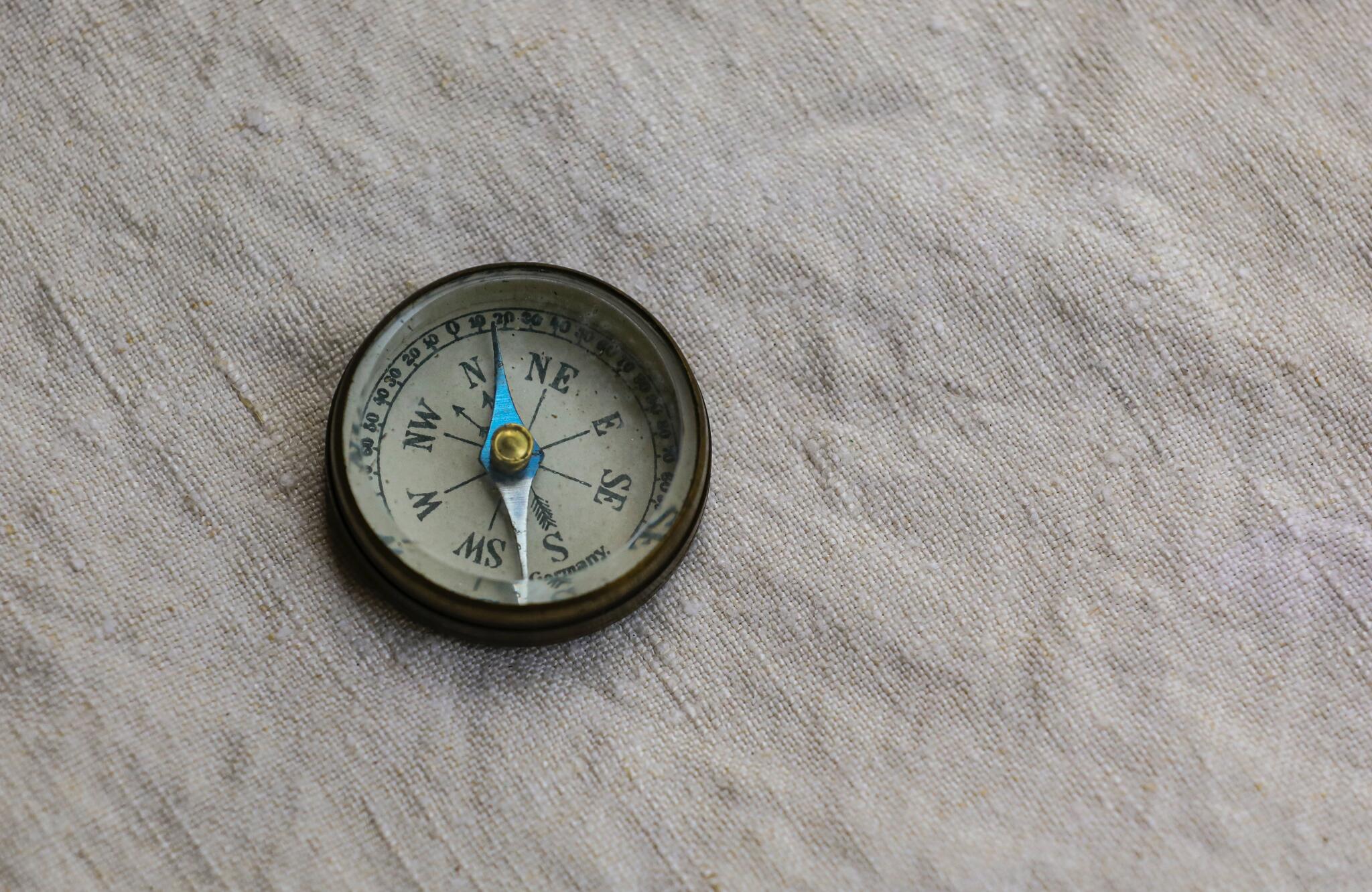 A compass sits on a beige linen cloth.