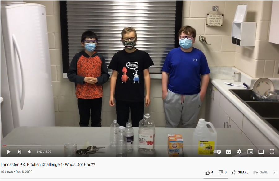 Screenshot of a video with students wearing masks preparing to do a science experiment.