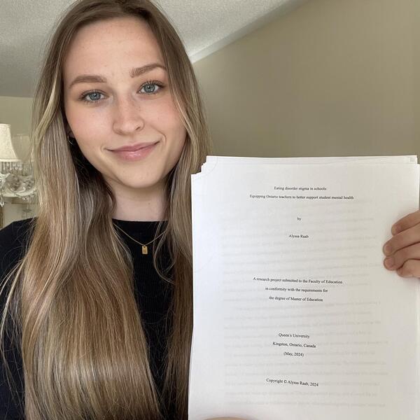 Alyssa Raab smiles holding a copy of her paper.