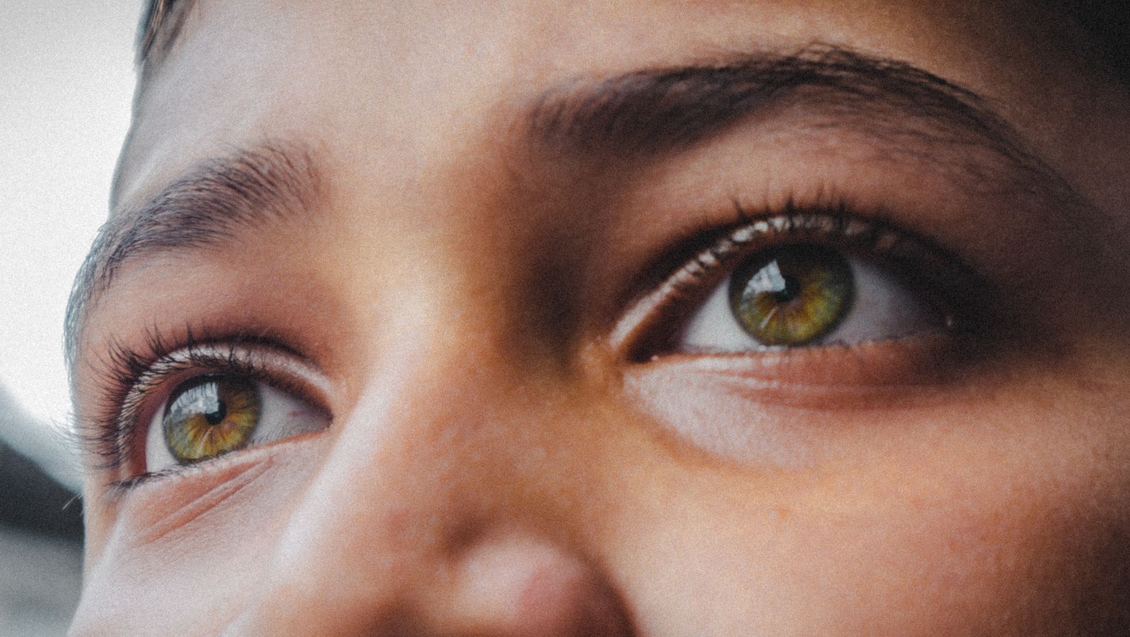 A photo of the top of someone's face with green eyes.