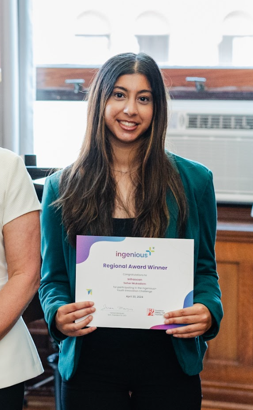 Seher Mukadam smiling at the camera holding a 'Regional Award Winner' certificate