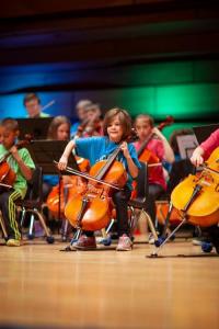 A photo of a child playing the cello at a year end showcase performance