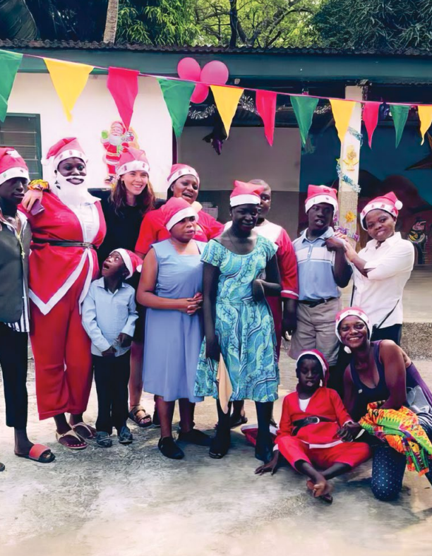 Laadi Safiul poses with her students outside wearing Santa hats.