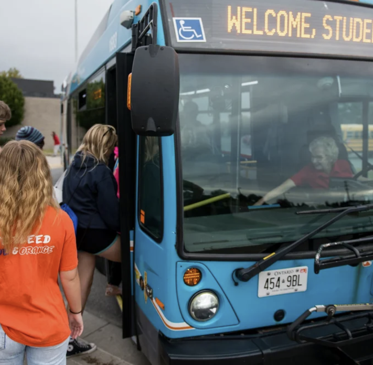 Students walk on to a bus in the summer.